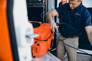 water damage restoration technician taking equipment out of van