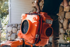 fire damage restoration technician carrying equipment into house