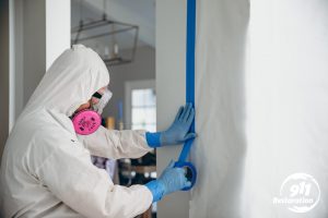 disaster restoration technician putting tape on wall